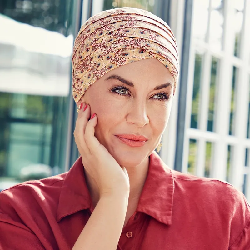 Femme souriante portant un bonnet chimio en bambou aux jolis motifs.